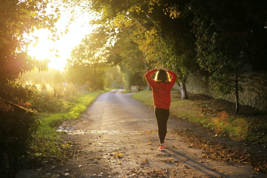 Woman walking on a sunlit country road at sunset