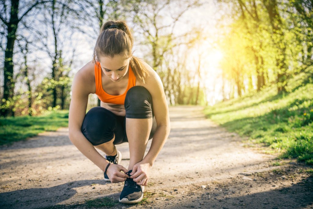 Woman tying her running shoe on a park path