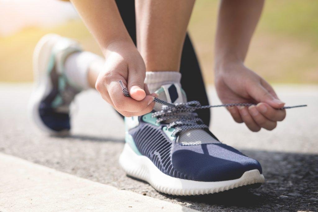Person tying a running shoe on a road