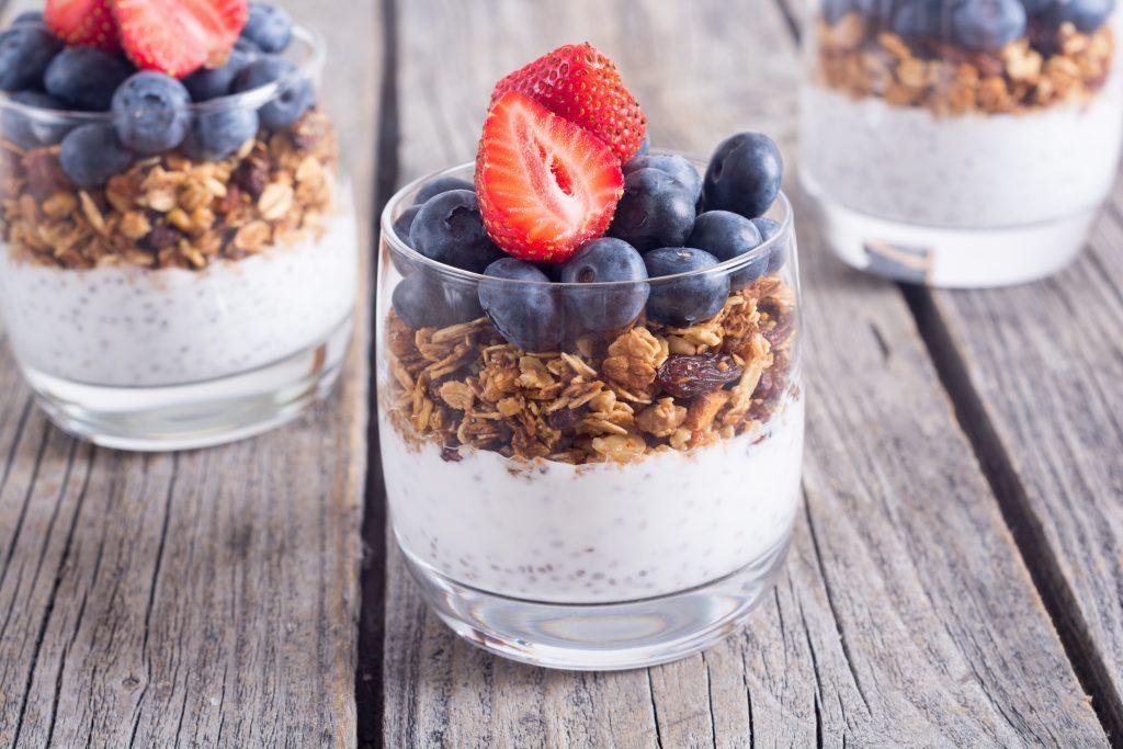 Yogurt parfait topped with granola, blueberries, and sliced strawberries