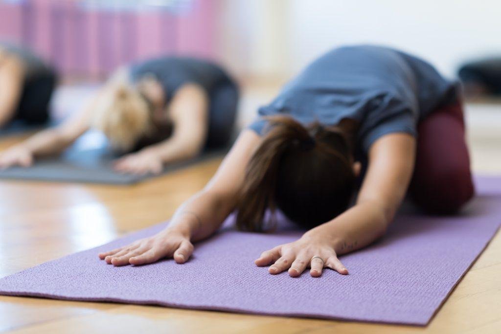 People in a yoga class doing a forward stretch on mats