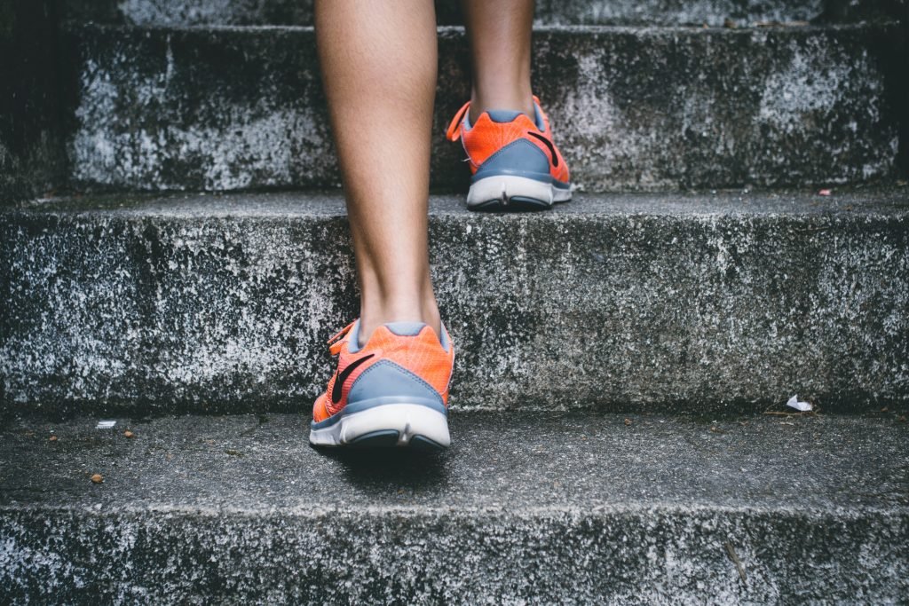 Person walking up concrete steps in orange running shoes