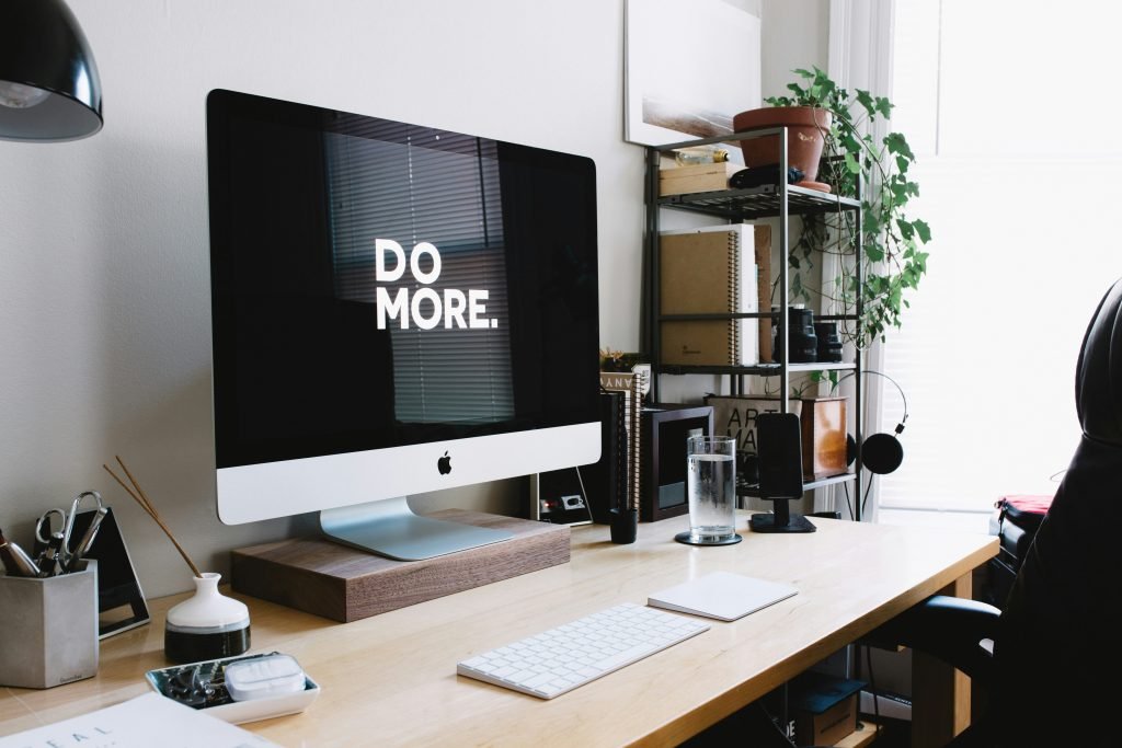 Home office desk with an iMac displaying “DO MORE.”