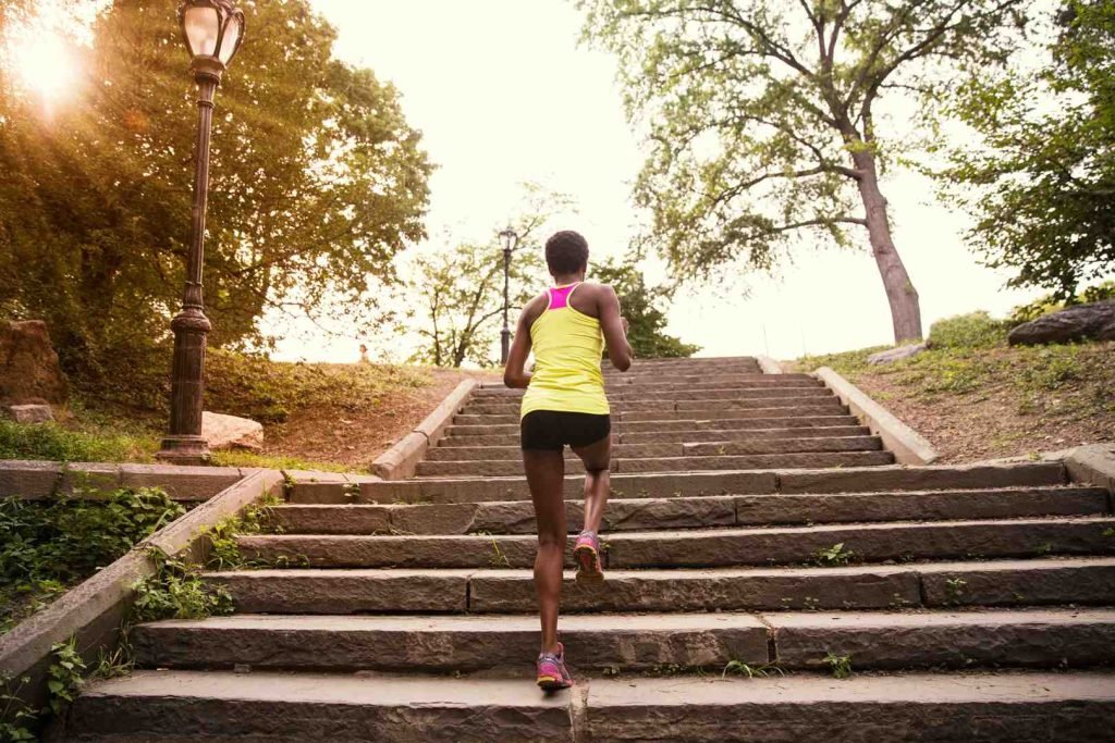 Woman running up stone steps in a park at sunset