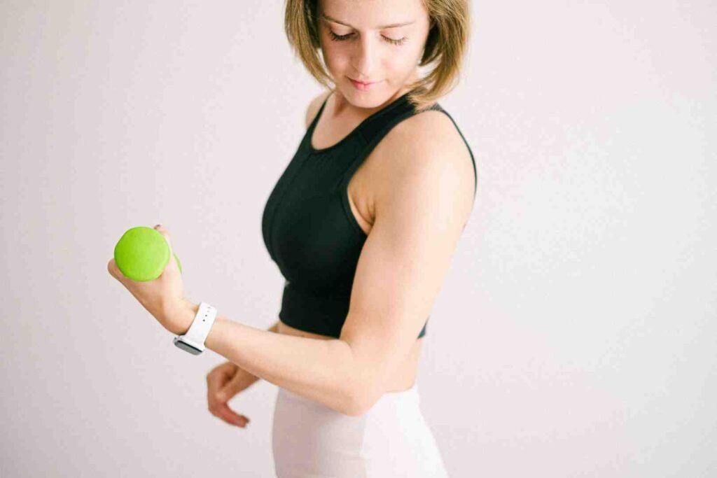 Woman holding a green dumbbell and checking her fitness tracker